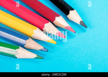 Matite multicolore vivaci disposte a ventaglio su sfondo blu. Le matite sono ben organizzate e creano un'atmosfera accattivante e accattivante Foto Stock