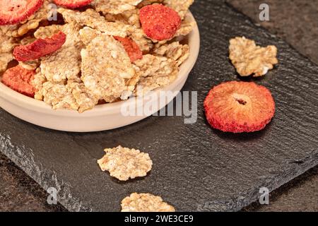 Iniziate la giornata con una sana colazione a base di fiocchi di grano con fragole dolci e secche e un pizzico di latte fresco, una deliziosa e nutriente bevanda Foto Stock