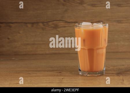 Un bicchiere di tè al latte tailandese ghiacciato Cha Yen su un tavolo di legno, spazio copia per testo Foto Stock