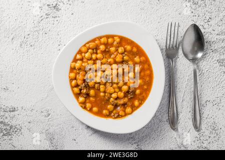 Stufato di ceci con carne macinata su un piatto di porcellana bianca su un tavolo di pietra Foto Stock