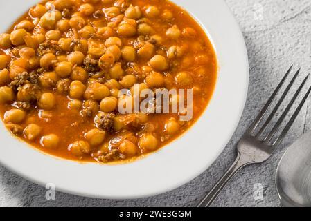 Stufato di ceci con carne macinata su un piatto di porcellana bianca su un tavolo di pietra Foto Stock