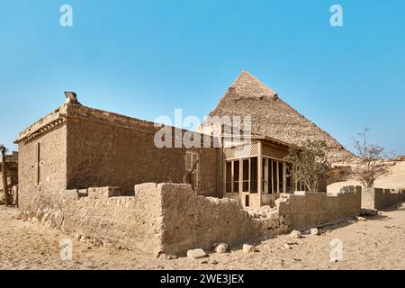 Giza, Egitto - 24 dicembre 2023: Piramide di Khafre (letto anche come Khafra, Khefren) nell'altopiano di Giza e vecchia casa di adobe Foto Stock