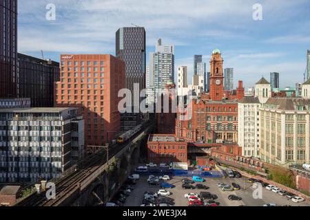 Immagine tratta da 86 Princess Street, Manchester, guardando verso il centro della città con un viadotto ferroviario e un treno, la torre dell'orologio di Kimpton e Deansgate Square Foto Stock