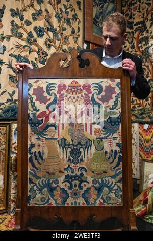 Londra, Regno Unito. 23 gennaio 2024. Un membro dello staff presenta "a (probably) French Needlework picture", XVIII secolo, sullo stand Textile Antiques alla London Antique Rug & Textile Art Fair (LARTA 2024) all'Evolution London di Battersea Park. Tessuti, arazzi e tappeti rari, alcuni risalenti a diversi secoli fa, sono in vendita durante lo spettacolo che si svolge fino al 28 gennaio 2024. Crediti: Stephen Chung / Alamy Live News Foto Stock