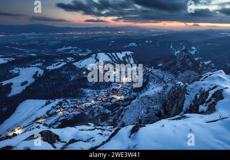 Villaggio di montagna invernale dei Carpazi in luce con case di legno su una collina ricoperta di neve fresca. Foto Stock