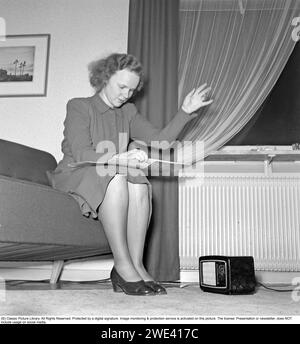 Radio negli anni '1940 Una giovane donna sta ascoltando la radio a casa, muovendo il braccio quando sente la musica. 1944 Krisotffersson rif. L179-2 Foto Stock