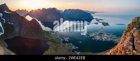 L'ampio panorama da Reinebringen rivela il sole di mezzanotte sull'arcipelago delle Lofoten, Norvegia, con il villaggio di Reine annidato Foto Stock