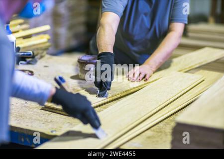 operai che assemblano pavimenti in legno insieme in fabbrica Foto Stock