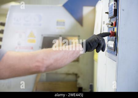mano del lavoratore che attiva il pulsante di una macchina Foto Stock