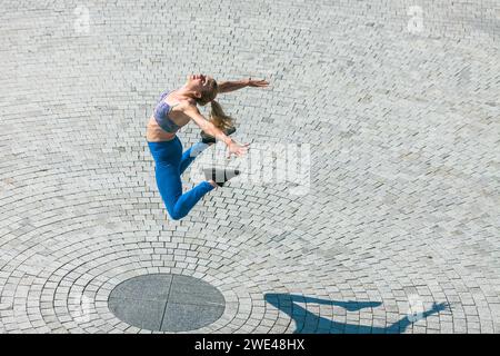 giovane donna in forma e muscolosa che salta in alto Foto Stock