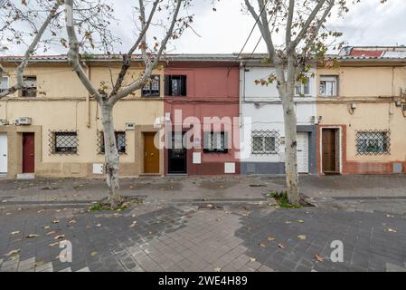 Passeggiata in ciottoli con alberi e pozzi di alberi di fronte a un quartiere di case unifamiliari a due piani Foto Stock