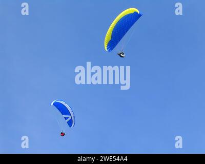 Primo piano di due parapendio sotto un cielo azzurro in una giornata di sole. Il parapendio è uno sport estremo o radicale Foto Stock