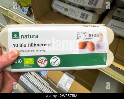 Baviera, Germania - 13 gennaio 2024: Un uomo tiene una scatola di uova biologiche in un supermercato *** Ein Mann hält eine Packung Bio Eier in einem Supermarkt Foto Stock