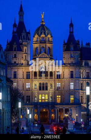 Schwerin, Germania. 23 gennaio 2024. La cupola dorata del castello di Schwerin è illuminata di sera. Il castello fu la residenza dei duchi e granduchi del Meclemburgo per secoli ed è ora la sede del parlamento statale del Meclemburgo-Vorpommern. Credito: Jens Büttner/dpa/Alamy Live News Foto Stock