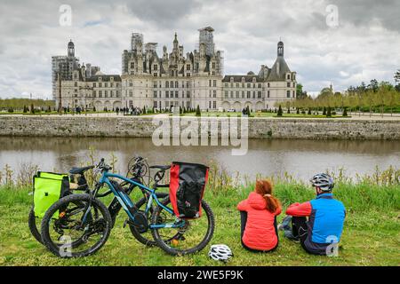 Uomo e donna in bicicletta sulla pista ciclabile della Loira fai una pausa e guarda il Château de Chambord, i castelli della Loira, la Valle della Loira, il sito patrimonio dell'umanità dell'UNESCO Foto Stock