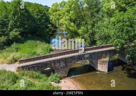 Vista aerea di un ciclista che attraversa un ponte di pietra sul fiume Haune nella regione di Hessisches Kegelspiel, Burghaun Rothenkirchen, Rhön, Assia, tedesco Foto Stock