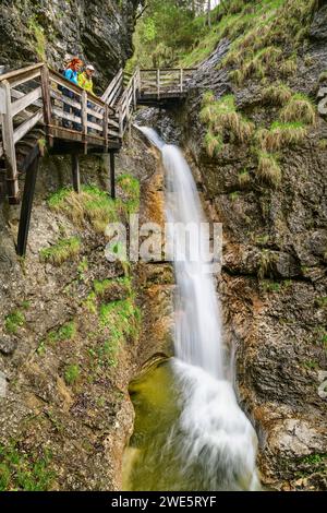 Uomo e donna che camminano attraverso la Gola di Strohwollner e osservano la cascata, la Gola di Strohwollner, il percorso delle Gole, le Alpi Berchtesgaden, Salisburgo, Austr Foto Stock