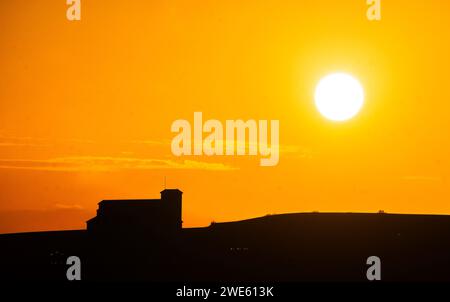 Tramonto nel borgo medievale di Lerma in una giornata di caldo torrido con la silhouette di una montagna e una chiesa negli ultimi raggi del sole pomeridiano. Foto Stock