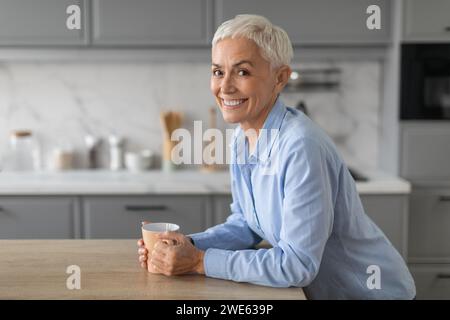 la signora anziana ama godersi una piacevole mattinata con una tazza di caffè al coperto Foto Stock