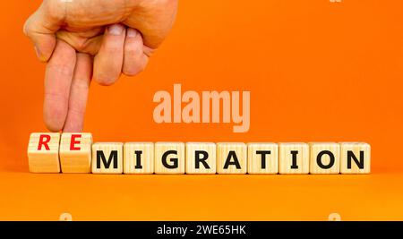 Simbolo di migrazione o di remigrazione. Concetto di Migration Remigration su bellissimi cubi di legno. Splendido sfondo arancione. Mano d'affari. Affari Foto Stock