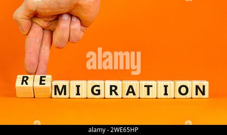 Simbolo di migrazione o di remigrazione. Concetto di Migration Remigration su bellissimi cubi di legno. Splendido sfondo arancione. Mano d'affari. Affari Foto Stock