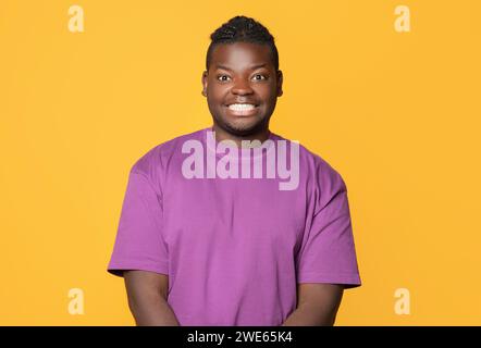Ragazzo nero che posa sorridente a camera su sfondo giallo Foto Stock