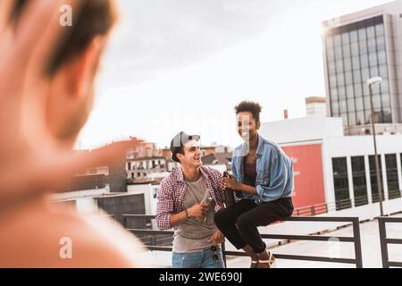 Amici felici che festeggiano con la birra sul tetto Foto Stock