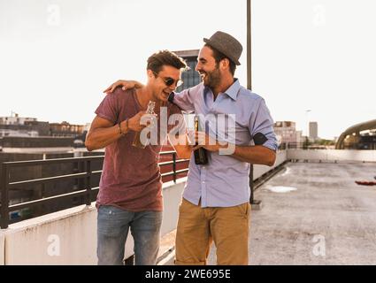 Uomini sorridenti che bevono birra e si divertono sul tetto Foto Stock