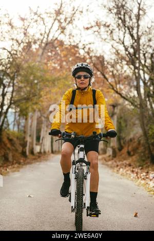 Donna in mountain bike su strada nella foresta Foto Stock