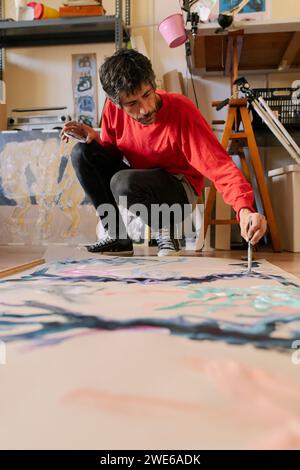 Artista maturo che si accovaglia e dipinge su tela in officina Foto Stock