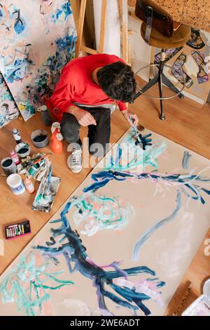 Artista maturo che dipinge su tela con pennello presso lo studio d'arte Foto Stock