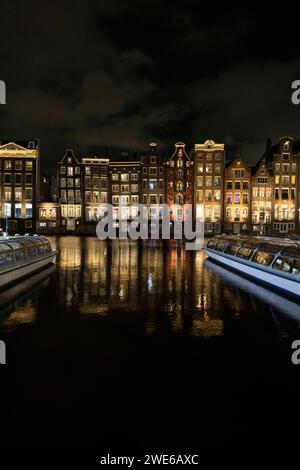 Edifici illuminati vicino al fiume di notte nella città di Amsterdam Foto Stock