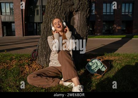 Le donne amano ascoltare la musica con le cuffie wireless nel parco Foto Stock