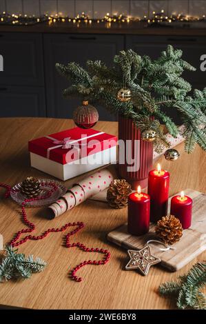 Candele rosse con scatola regalo vicino all'albero di Natale decorato sul tavolo Foto Stock