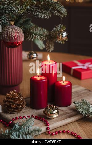 Candele rosse accese vicino all'albero di Natale in vaso sul tavolo Foto Stock