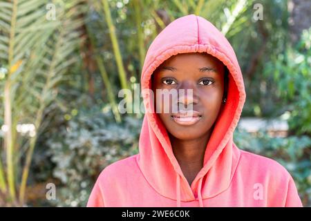 Giovane donna che indossa una camicia rosa con cappuccio al parco Foto Stock