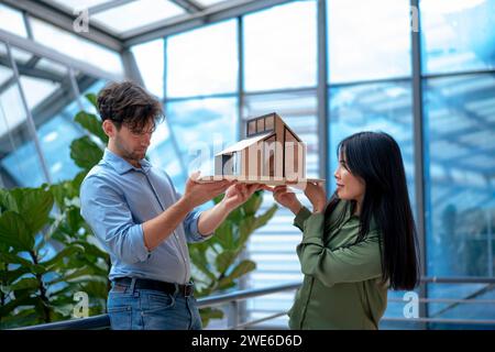 Architetti multirazziali che esaminano la casa modello in ufficio Foto Stock