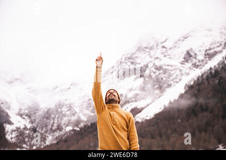 Uomo sorridente che punta verso il cielo di fronte ai Pirenei, Catalogna, Spagna Foto Stock