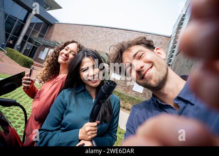 Giovane che scatta selfie con gli amici alla stazione di ricarica Foto Stock