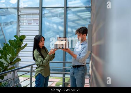 Architetti multirazziali che esaminano la casa modello in piedi nel corridoio Foto Stock