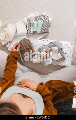 Donna incinta che porta a casa i vestiti del bambino Foto Stock