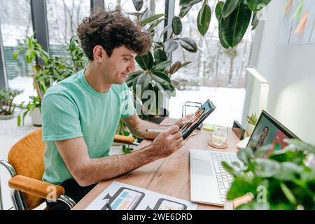 Web designer sorridente che disegna su un tablet PC alla scrivania Foto Stock