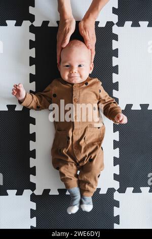 Bambino sorridente sdraiato sul tappetino a casa Foto Stock