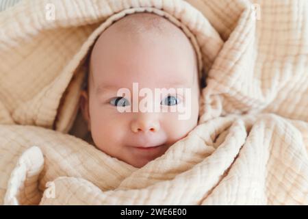 Un simpatico bambino sorridente avvolto in una coperta Foto Stock