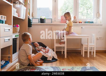 Bambino con fratelli in camera da letto a casa Foto Stock