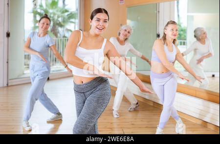 Ballerine femminili allegre ed energiche di diverse età imparando nuovi passi di ballo in una moderna lezione di fitness Foto Stock