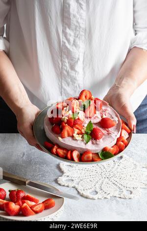 Mani di donna che reggono il piatto con crostata vegana di fragole pronta da mangiare Foto Stock