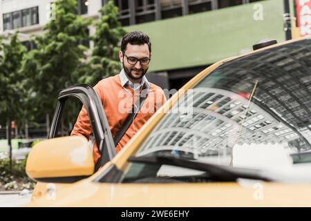 Uomo d'affari che indossa occhiali da vista e sale in taxi Foto Stock