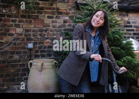 Donna felice in bicicletta vicino all'abete Foto Stock