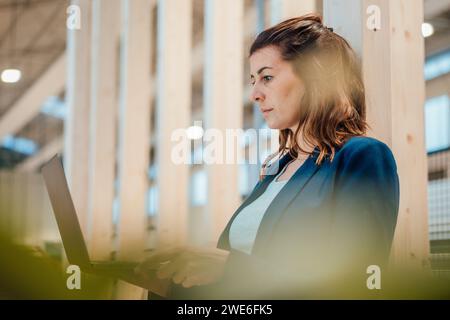 Donna d'affari concentrata che lavora su notebook nel settore Foto Stock